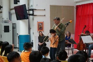 HK Phil trombonist pretends to use a schoolboy's head as a mute.