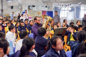 Brass players surrounding the audience, letting the children experience a special performance.